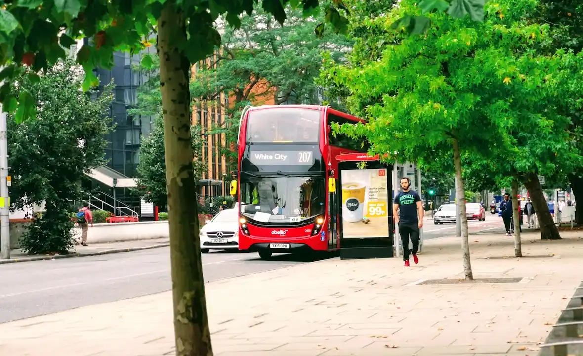 A red double decker bus standing at a bus stop in London